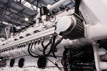 Poster - A large engine with many parts is shown in a factory. The engine is made of metal and has a lot of pipes and valves. Concept of industrialization and the complexity of machinery