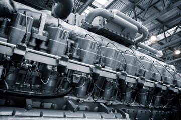 Poster - A large engine with many parts is shown in a factory. The engine is made of metal and has a lot of pipes and valves. Concept of industrialization and the complexity of machinery
