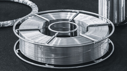 Poster - A silver wire is on a black surface. The wire is twisted and bent. The wire is surrounded by a metal frame