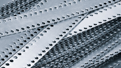 Poster - A pile of metal pieces with holes in them. Blue  holes are of different sizes and shapes. The metal pieces are arranged in a way that they form a pattern. Concept of order and structure