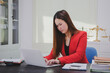 © Sorasit - Asian businesswoman, focused , sits at ablack wooden table. Surrounded by notes , she strategizes her next move, embodying confidence and professionalism in her workspace.