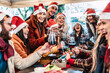 © charmedlightph - Happy people wearing santa claus hat having Christmas dinner party - Cheerful group of friends toasting red wine and celebrating new year together - Happy winter holidays concept