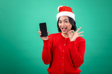 An Asian woman in a red sweater and Santa hat winks and holds up a smartphone, showing an 