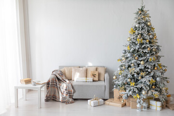 Wall Mural - Snow-covered Christmas tree with gifts decorated with toys in the interior of a white room for the new year