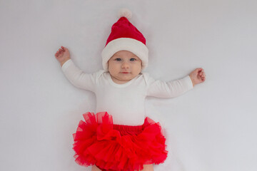 Baby girl in a Santa hat on a light background.holiday.