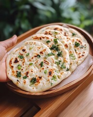 Canvas Print - Freshly baked naan bread with cilantro and green onions on a wooden plate.