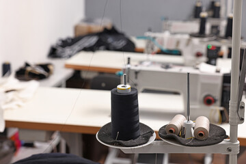 Sewing machines with spools of thread in professional workshop, closeup