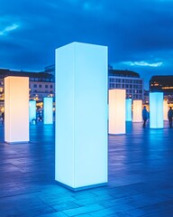 Wall Mural - Illuminated pillars glowing in a plaza with blurred people walking by at dusk.