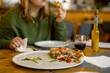 © mdyn - A woman holds a piece of pizza in hands. Focus on a pizza. Pizza with prosciutto, ham, arugula, tomatoes and parmesan. Italian cuisine. Food banner