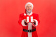 © khosrork - Portrait of happy positive elderly man with gray beard wearing santa claus costume giving present box, congratulating with new year holidays.