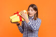 © khosrork - Curious amazed woman with brown hair unpacking yellow wrapped present box watching what inside