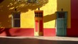 © Dario Berardi - Colori accesi e geometrie decise caratterizzano questa immagine con archi colorati su uno sfondo giallo e bianco, catturando il passaggio di una figura solitaria. Le tonalità vibranti dei portoni enfa