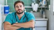© Pinklife - A confident male nurse in scrubs with folded arms sits in a hospital corridor, embodying the compassion and steadfastness essential in the nursing profession.