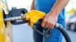 © Pinklife - A close-up image shows a person refueling a vehicle using a yellow gasoline nozzle, highlighting the concept of travel and energy efficiency in modern transportation.
