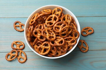 Tasty pretzel crackers on light blue wooden table, top view