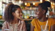 © Filirovska - Two women smiling and enjoying a conversation in a cozy cafe, with warm lighting and blurred background, creating a friendly and relaxed atmosphere
