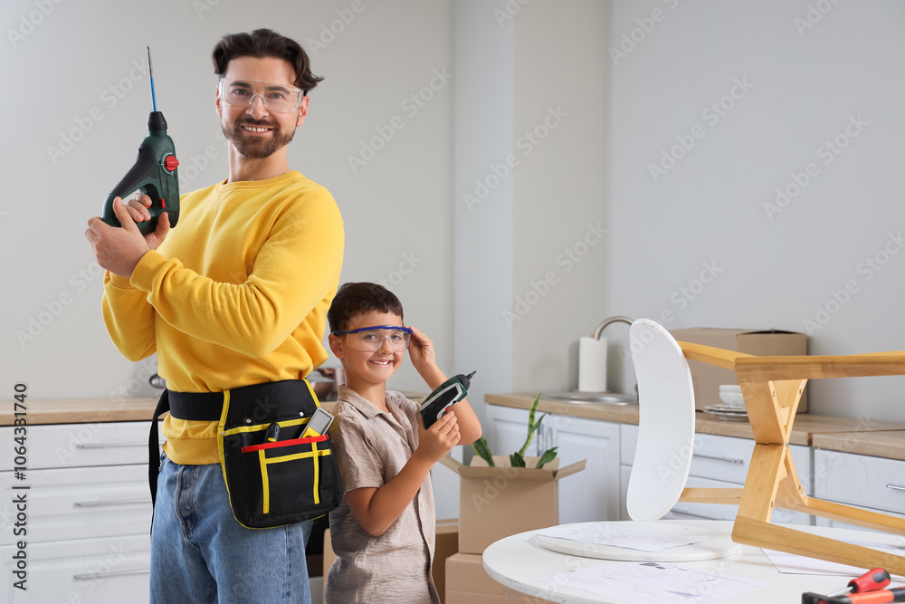 Father and his little son with drills assembling furniture in kitchen