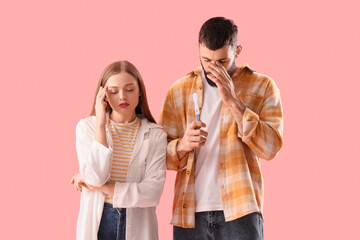 Wall Mural - Upset young couple with pregnancy test on pink background