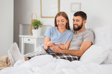 Wall Mural - Happy young couple with pregnancy test lying in bedroom