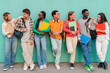 © Jose Calsina - Diverse Group of College or High School Students Share Cheerful Moments Between Classes, Carrying Colorful Folders and Backpacks While Leaning Against Vibrant Teal Wall, Teenage Classmates talking