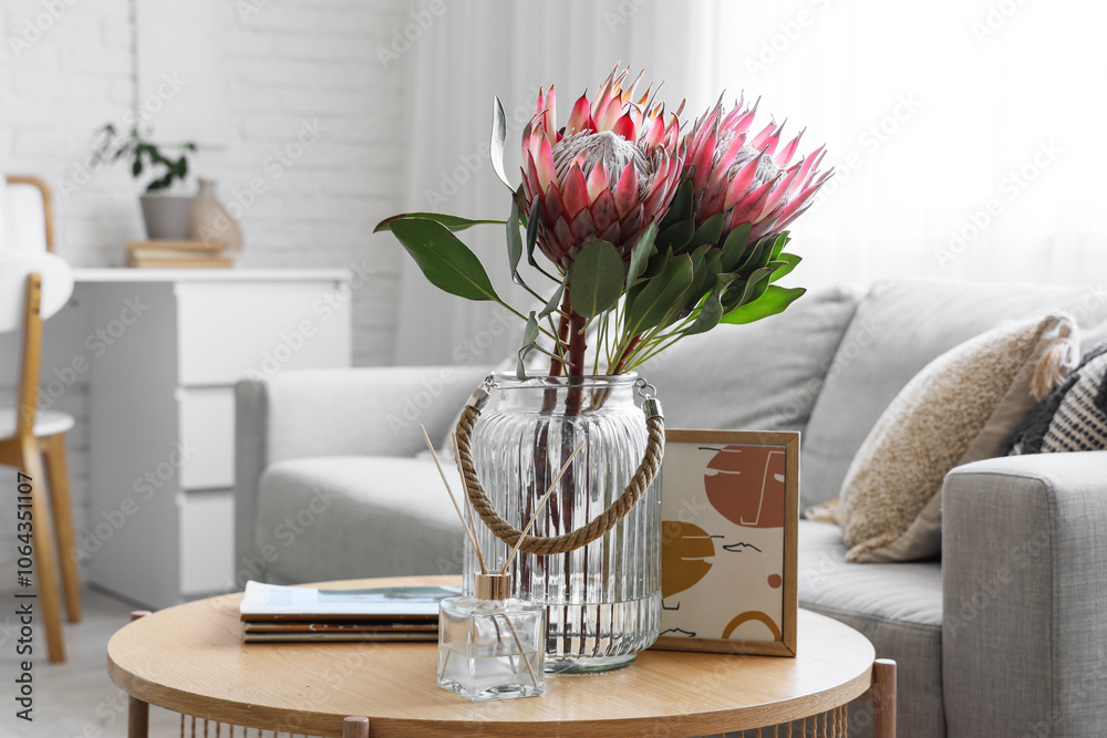 Vase with protea flowers, reed diffuser and magazines on table in living room, closeup