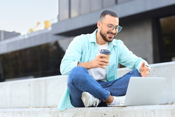 Canvas Print - Young man with laptop video chatting outdoors