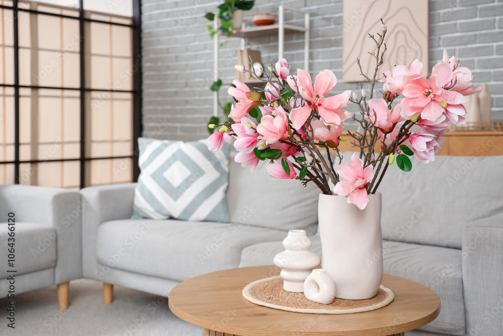 Vases with magnolia flowers on table in living room