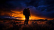 © John - A lone hiker gazes at a breathtaking sunset, with warm colors illuminating the sky. The mountainous landscape is bathed in evening light, creating a serene atmosphere.