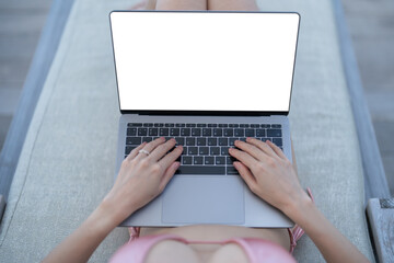 Hand with white blank laptop screen mockup with ocean background.