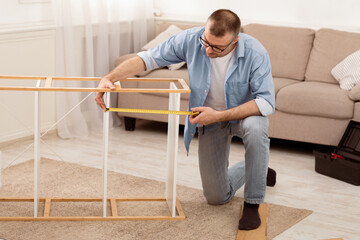 Aufkleber - Middle-Aged Man Installing Cabinet Using Measuring Tape Tool Assembling Furniture After Moving House. Home Furnishing Concept. Male Housework, Furniture Installation