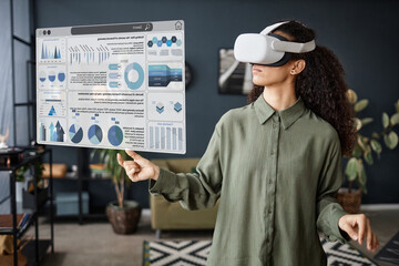 Young biracial woman standing in living room using VR headset for financial education