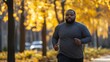 © Sawitree88 - A fat black man working out, a fit jogger strolling through a metropolitan park.