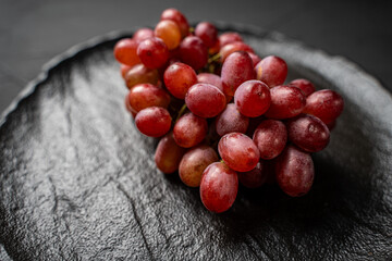 Bunch of Red Grapes on Black Mica Plate on Dark Background. Space for text.