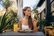 © standret - Delicious food. Beautiful young woman is outdoors of the restaurant by the table