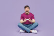 © ViDi Studio - Full body young Caucasian man wear violet t-shirt casual clothes sit hold in hand play pc game with joystick console isolated on plain pastel light purple background studio portrait Lifestyle concept