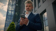 © Yuliia - Mature senior employer middle-aged Caucasian entrepreneur outdoors old business man looking at mobile phone thinking pensive ponder idea solution think male businessman in city browsing smartphone