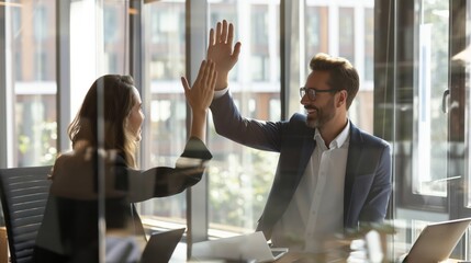 Poster - Two business professionals high-fiving each other while working in a modern office. They are celebrating a successful partnership or achievement, emphasizing teamwork and cooperation.