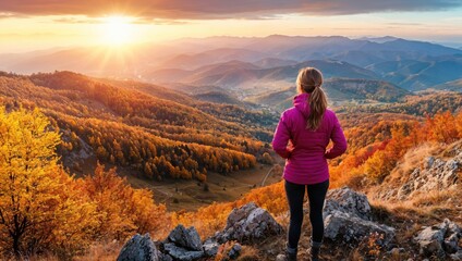 Poster - Woman stands on a mountain, overlooking a breathtaking landscape during sunset, surrounded by colorful autumn foliage.