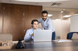 © fizkes - Diverse young male project managers working on marketing strategy at laptop together, using modern technology for teamwork, networking. Entrepreneur giving advice to coworker at workplace