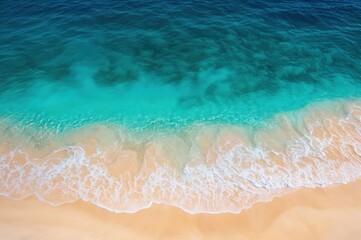 Poster - Blue ocean waves gently washing over sandy beach shore. Aerial view of turquoise sea and beige sand