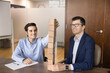 © fizkes - Happy motivated male business partners stacking toy blocks on table, building tower, symbol of teamwork, company growth, synergy, unity, success, enjoying collaboration, working on team spirit