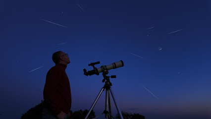 Amateur astronomer looking at the evening skies, observing planets, stars, Moon and other celestial objects with a telescope.