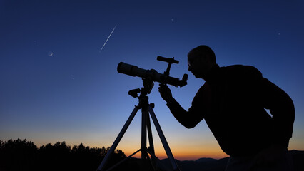 Amateur astronomer looking at the evening skies, observing planets, stars, Moon and other celestial objects with a telescope.