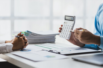 Financial planning consultant and meeting to discuss market situation analysis using financial charts in business reports. Businessman calculating finances by calculator.