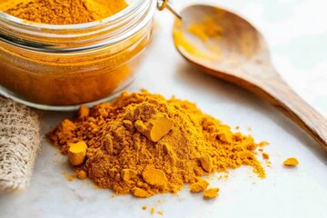 Aufkleber - A pile of bright turmeric powder rests next to an open glass jar on a light-colored surface, illustrating the earthy shade and inviting aroma of this popular spice.