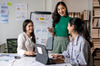 © Apichat - Three women are sitting around a table with a white board and a laptop