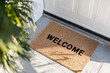 © vejaa - Door mat in front of entrance door with word Welcome on floor outdoors