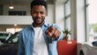© Gilberto - Excited young African-American man poses with car keys against a dealership backdrop allowing room for added messaging or text