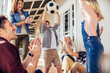 © Marko Geber - Family cheering as kids play with soccer ball on porch