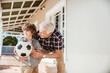 © Marko Geber - Grandfather and grandson playing with soccer ball on house porch